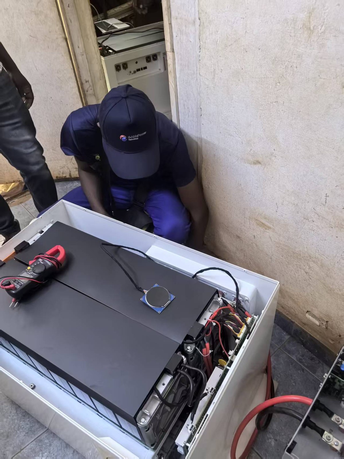 A team member working beside an open energy storage unit, with test equipment visible.