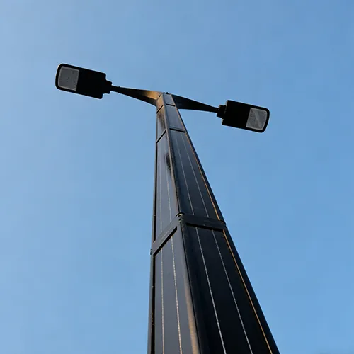 A low-angle view of a black hexagonal pole with integrated vertical solar panels and two street lamp heads extending from it against a clear
